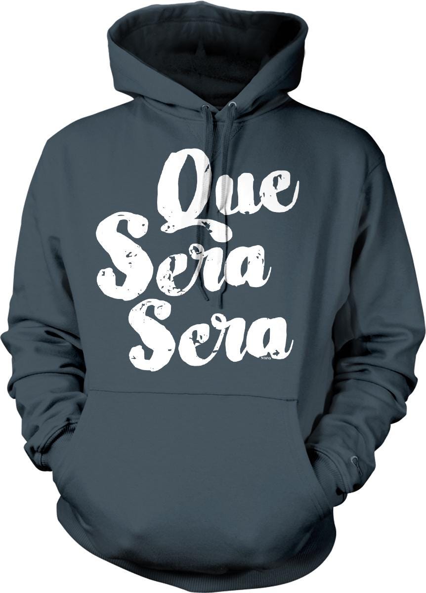 A dark grey hoodie with white text that reads "Que sera sera" printed on it.