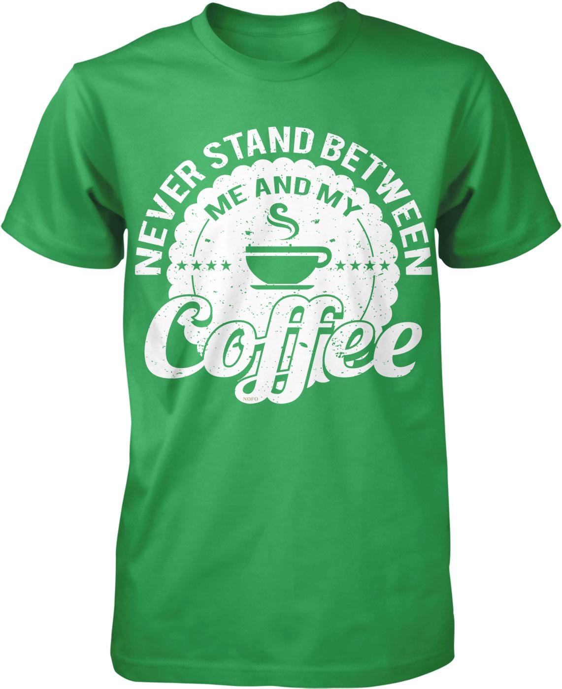 A green t-shirt with a white graphic design that says "NEVER STAND BETWEEN ME AND MY COFFEE" and features a coffee cup icon.