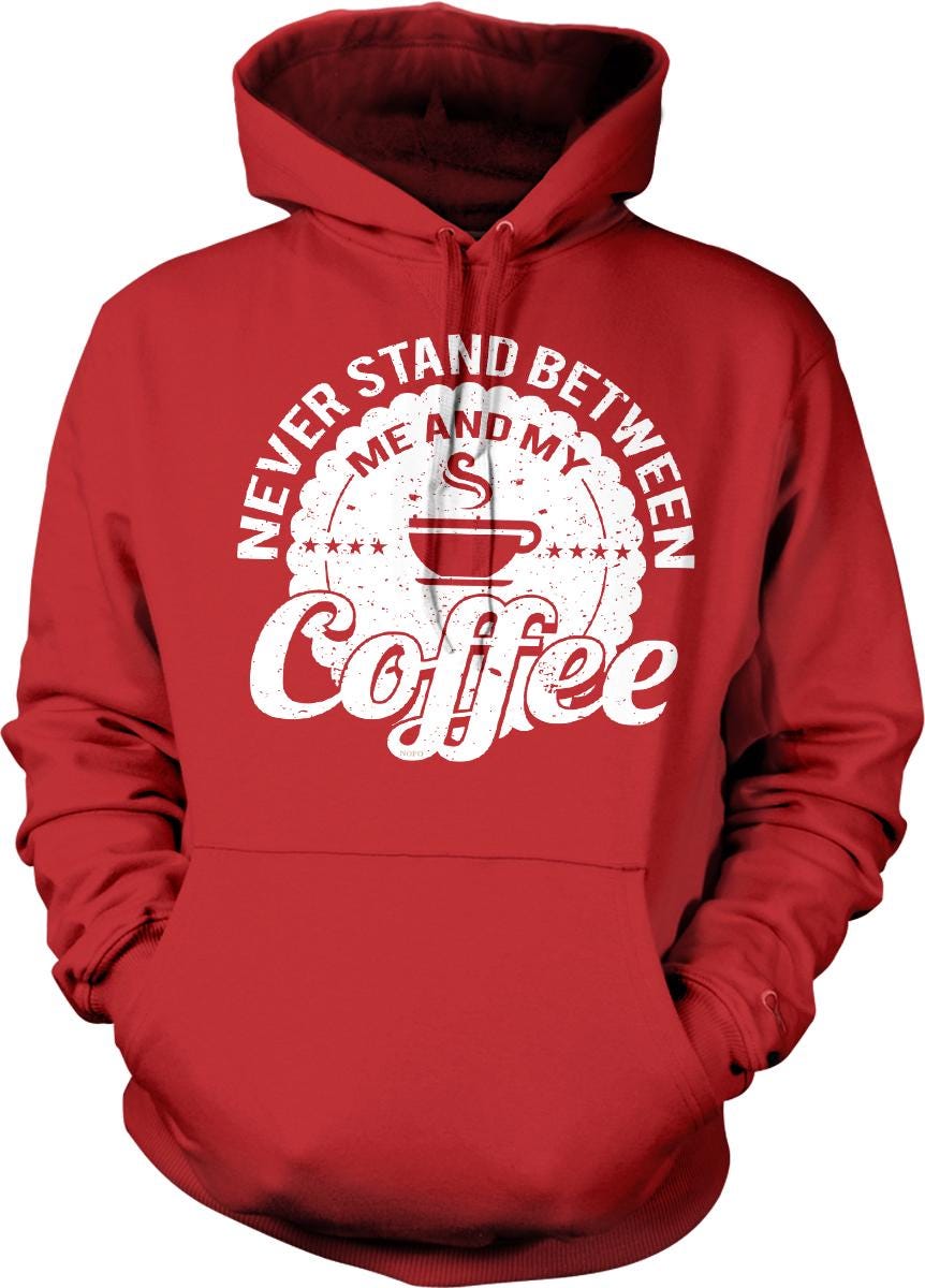 A red hoodie with a white graphic design that says "NEVER STAND BETWEEN ME AND MY COFFEE" printed on it.