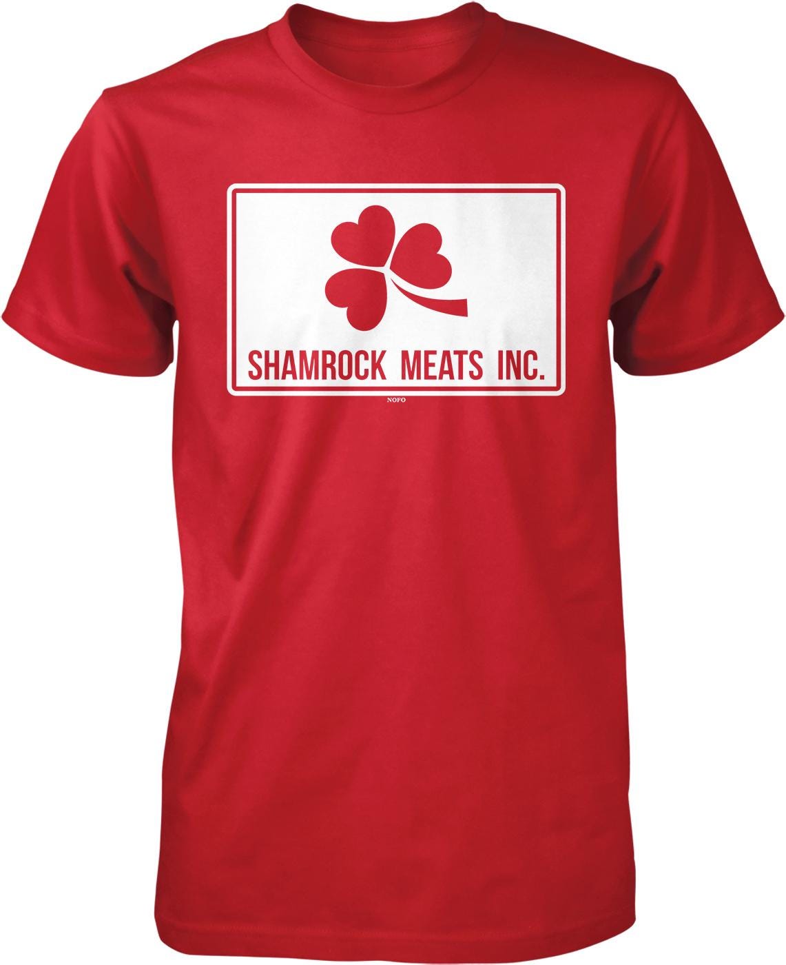 A red t-shirt with a white rectangle containing the text " Shamrock Meats Inc." and a red clover symbol.