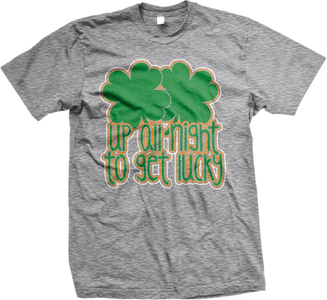 A gray t-shirt with a graphic design featuring two green shamrocks and the text "UP AT NIGHT TO GET LUCKY" printed on it.