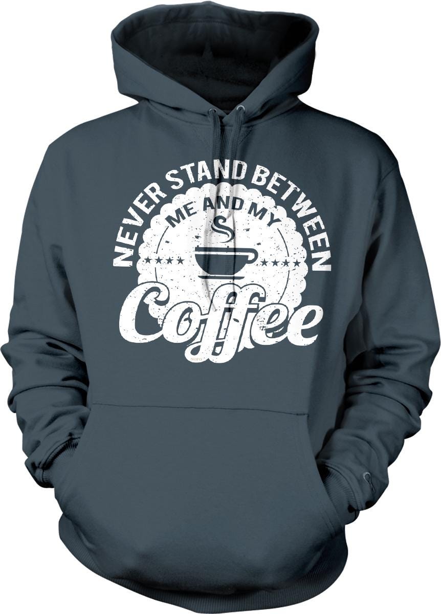 A gray hoodie with a white graphic design that says "NEVER STAND BETWEEN ME AND MY COFFEE" printed on it.