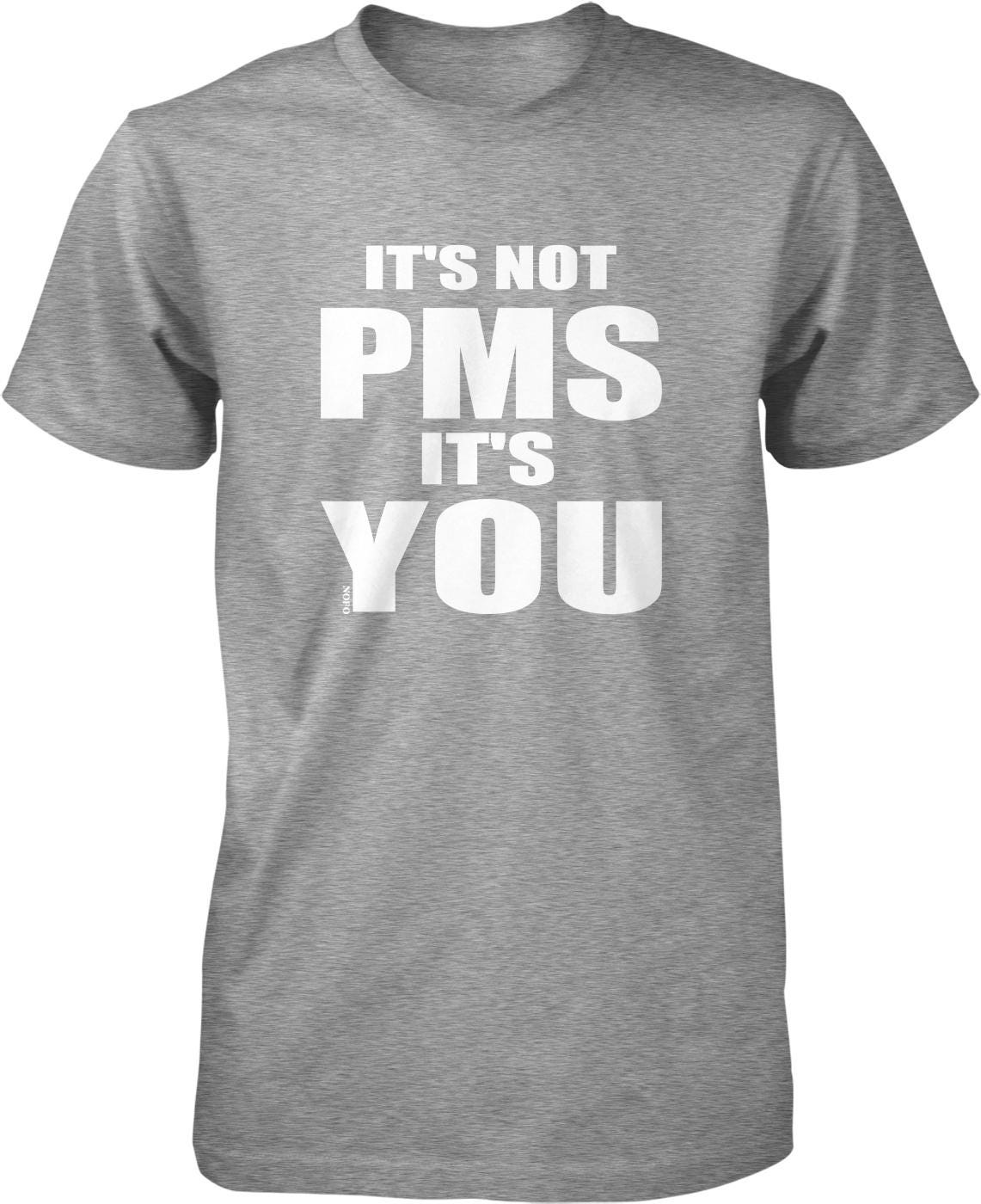 A gray t-shirt with the text "IT'S NOT PMS IT'S YOU" printed on it in white letters.