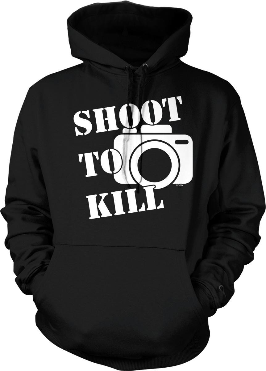 A black hoodie with the text "SHOOT TO KILL" printed on it, along with a graphic of a camera.