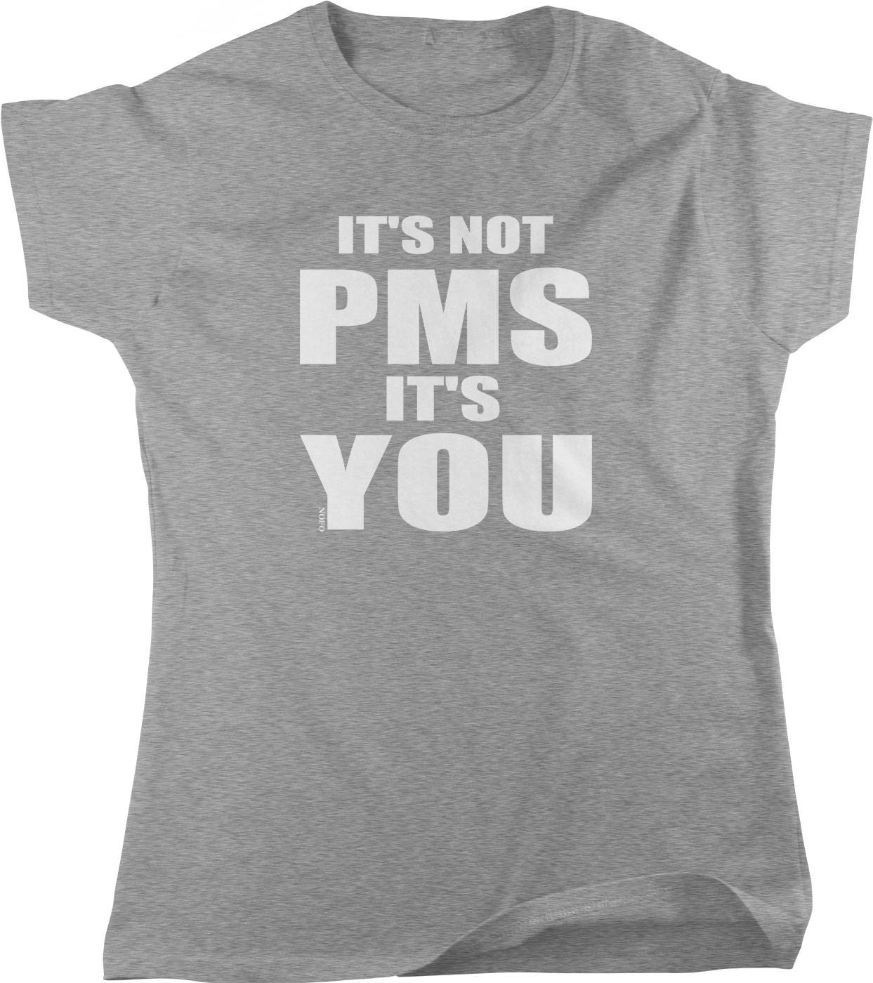 A gray t-shirt with the text "IT'S NOT PMS IT'S YOU" printed on it.