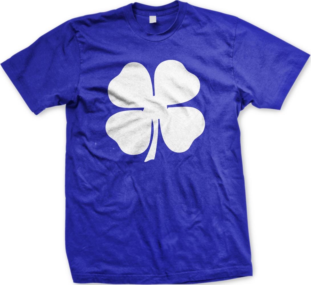 A blue t-shirt with a white four-leaf clover graphic printed on it.