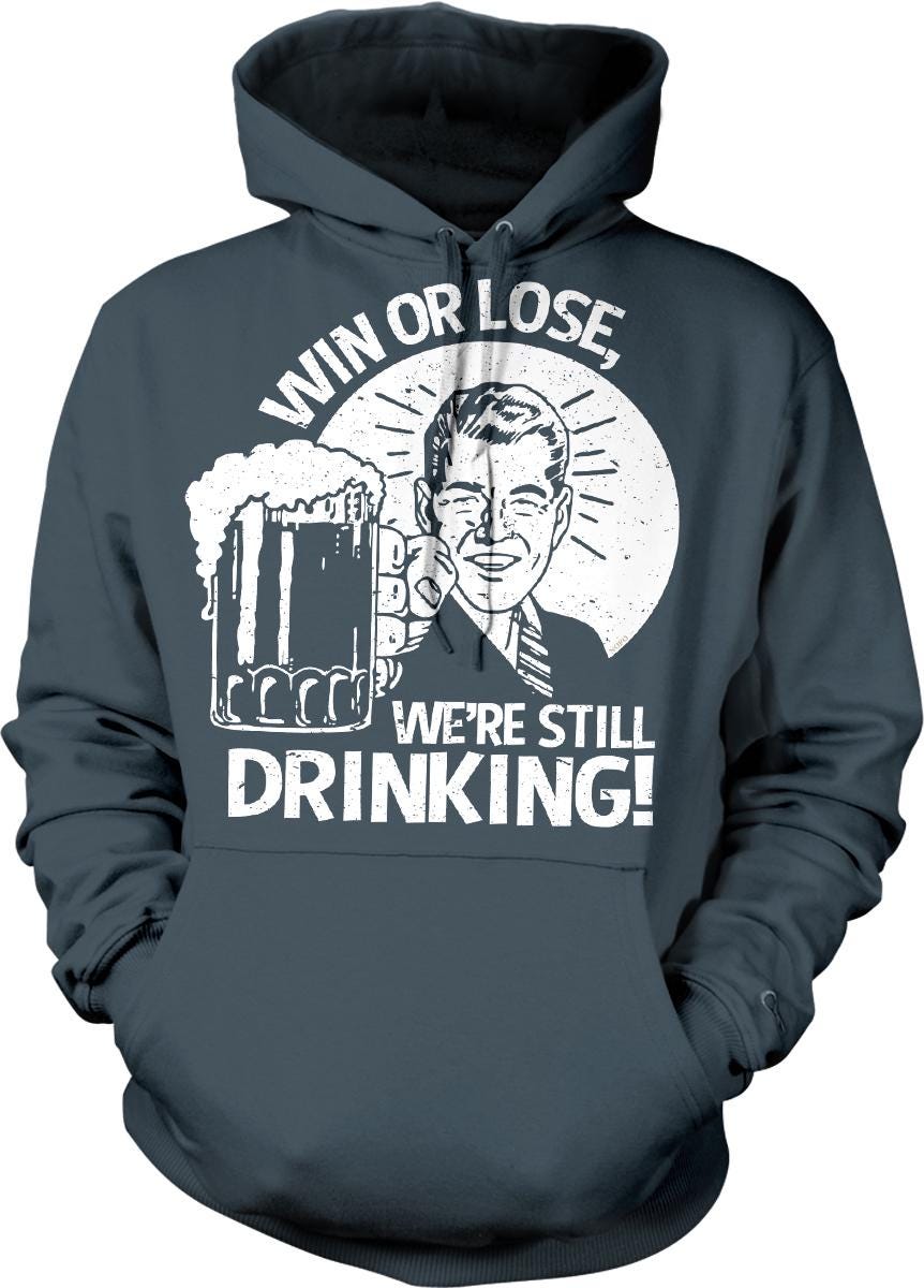 A gray hoodie with a graphic design featuring a man holding a beer mug and the text "WIN OR LOSE, WE'RE STILL DRINKING!"