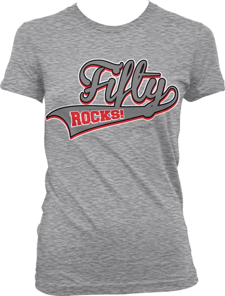 A gray t-shirt with a graphic design featuring the text "Fifty Rocks!" in a stylized font.