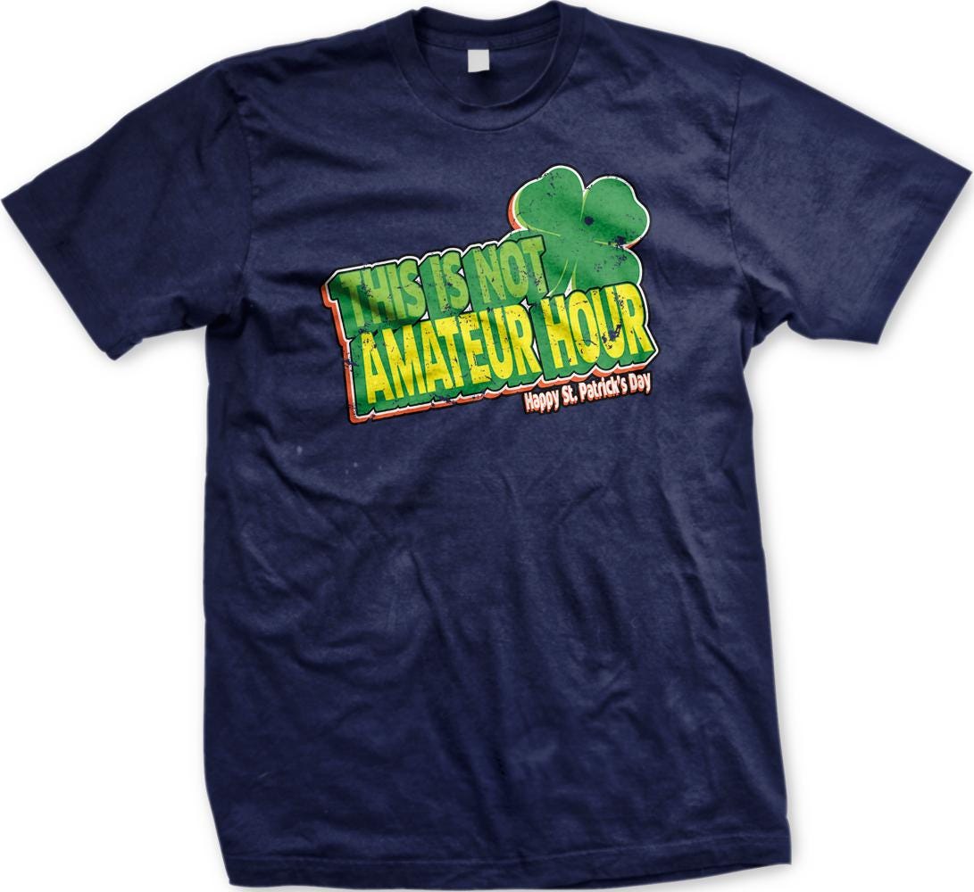 A navy blue t-shirt with a graphic design featuring a clover and text that reads "This is not Amadeur Hour Happy St. Patrick's Day".