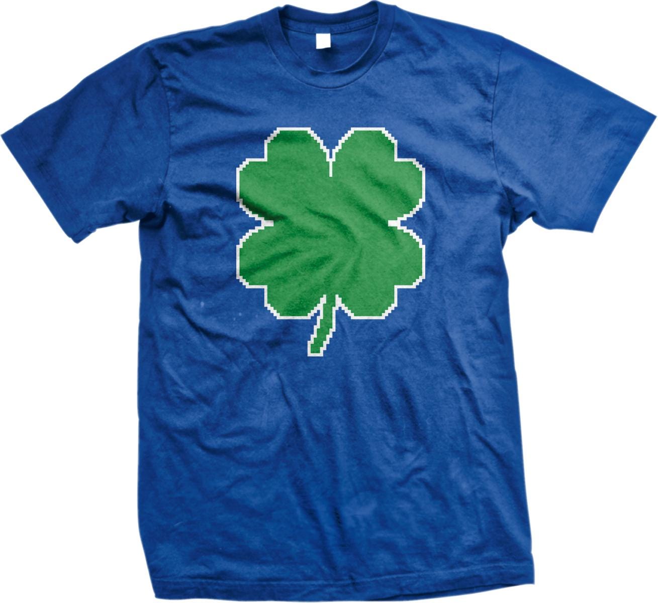 A blue t-shirt with a green pixelated four-leaf clover design printed on it.