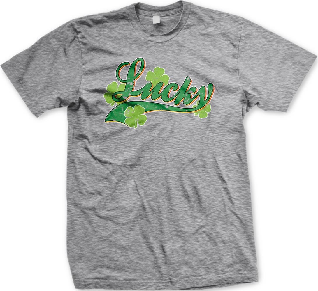 A grey t-shirt with a graphic design featuring the word "Lucky" surrounded by four green shamrocks.