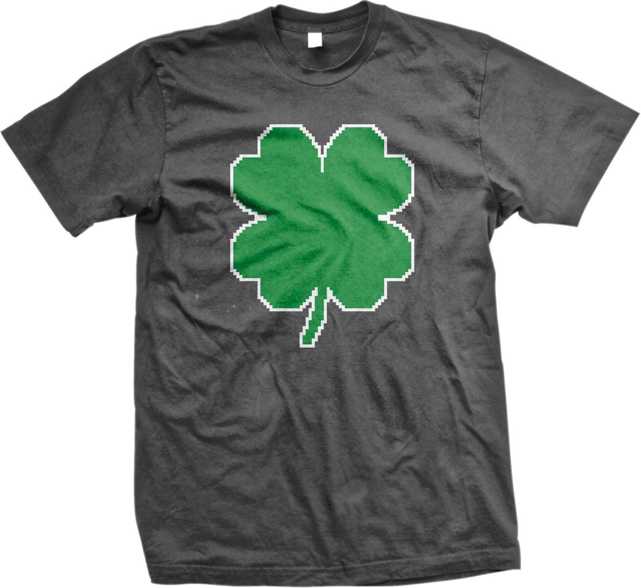 A gray t-shirt with a green pixelated four-leaf clover design printed on it.