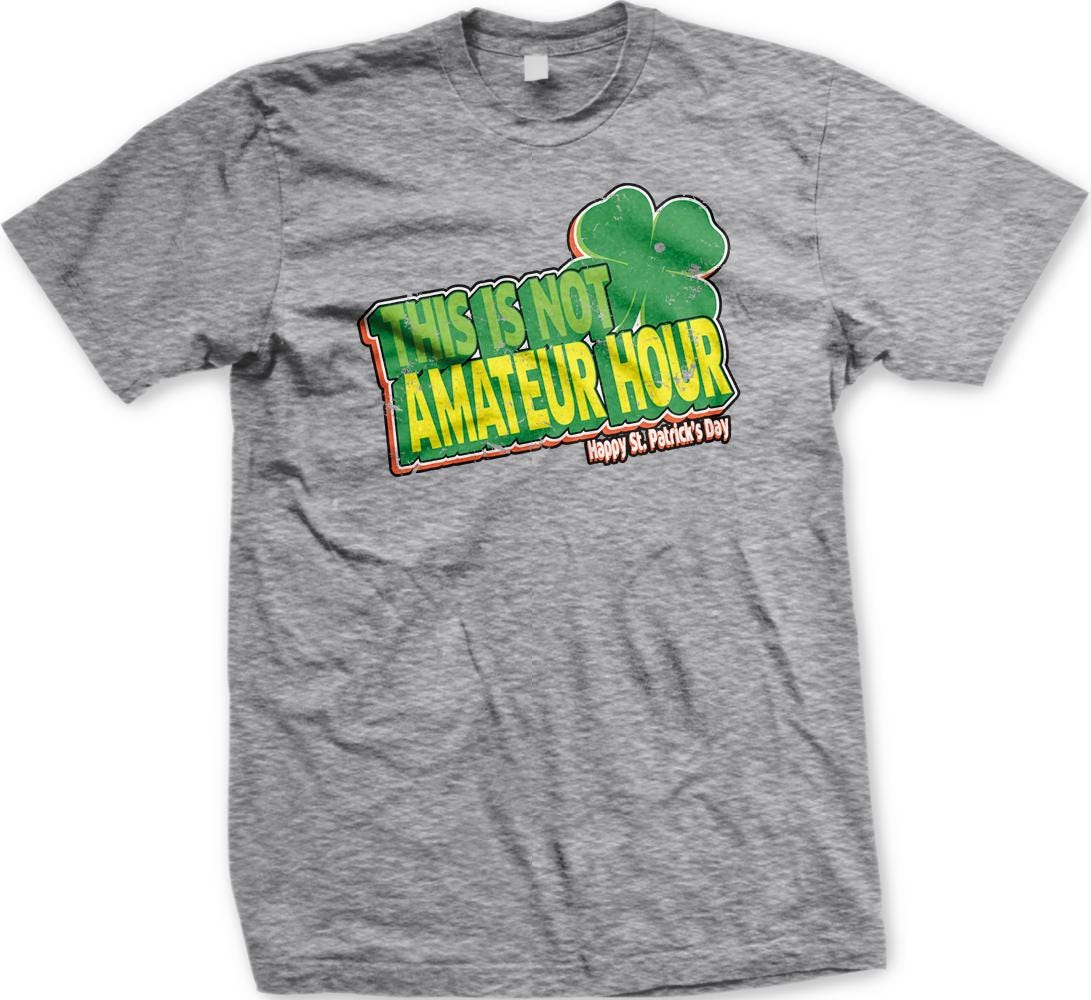 A gray t-shirt with a graphic design featuring a clover and text that reads "This is not amateur hour Happy St. Patrick's Day".